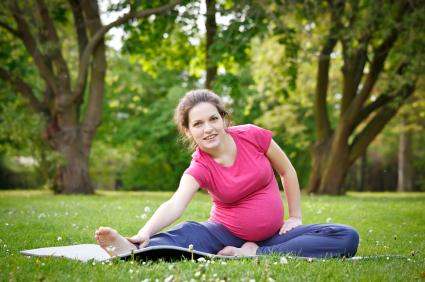 pregnant woman stretching on mat outdoors