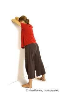 A woman leaning forward against a wall