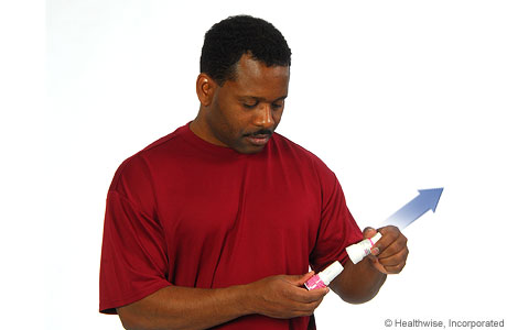 Man removing the cap from the inhaler