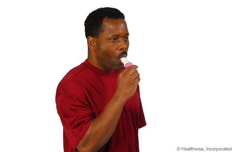 Man placing the inhaler in his mouth