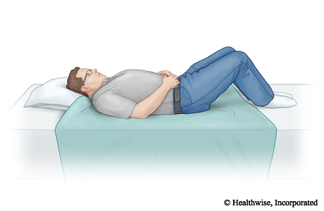 A sheet folded in half and placed on the bed between where the person's knees and head will be