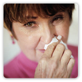 Photo of a woman with allergies holding a tissue to her nose