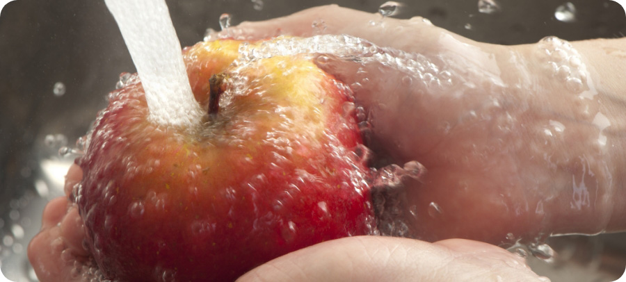 Close up of hands washing an apple.