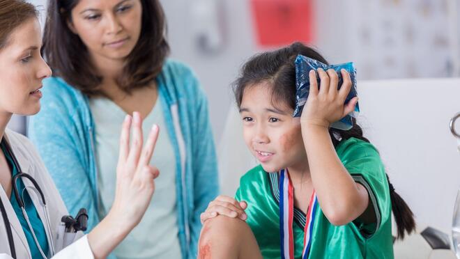 Child holding ice pack to head and doctor holding up 3 fingers