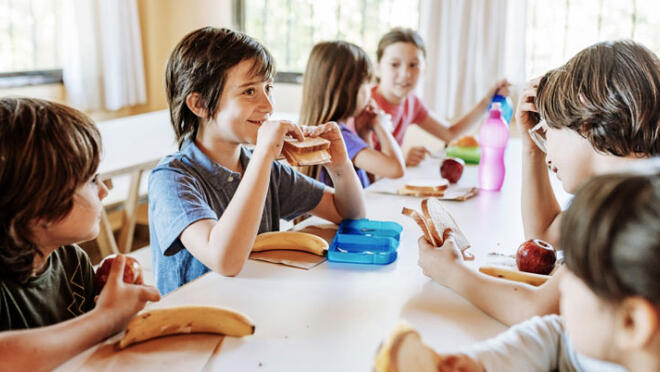 a group of children at a table enjoying healthy food.