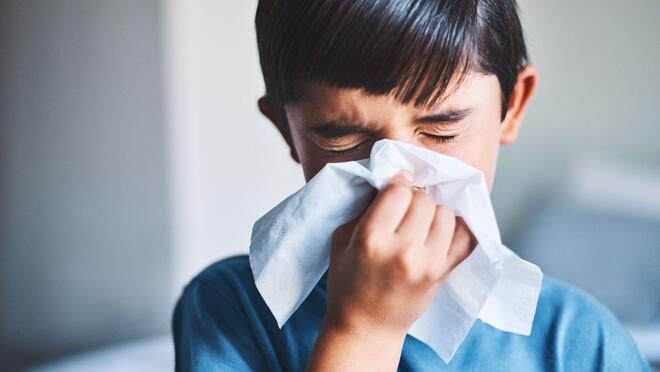 Child blowing their nose with tissue