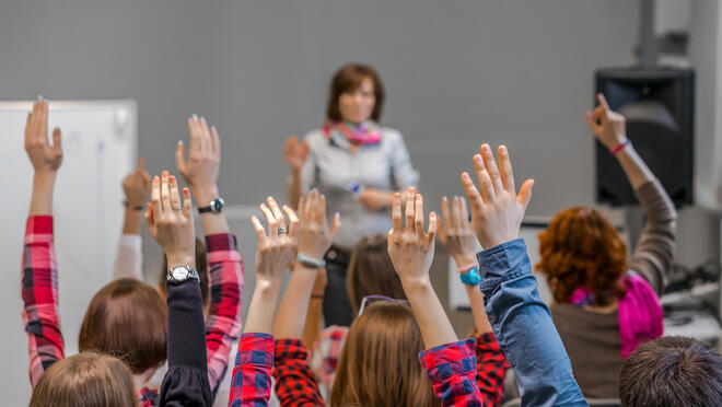 Adults raising hands to answer a question.
