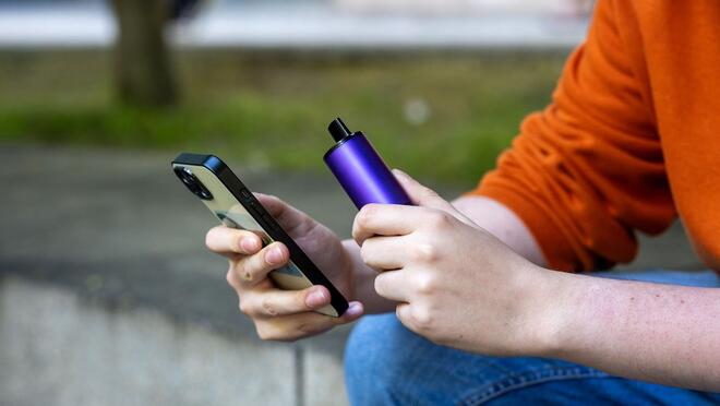 Person holding phone and vape pen