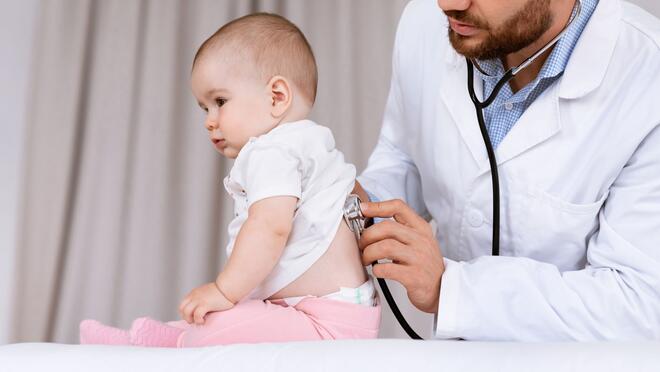 Doctor using stethoscope on baby's back