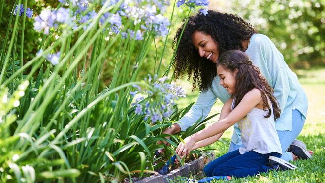 Adult and child kneeling in a flower garden