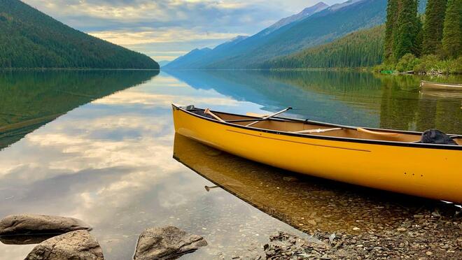 Yellow canoe beached on a lakeside with mountain backdrop
