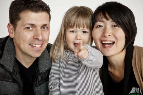 parents with toddler girl pointing at camera