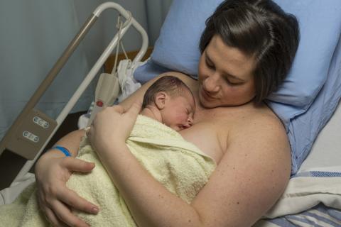 mom hugging newborn baby to her chest