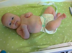 baby with cloth diaper lying on bed
