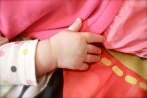 close up of baby's hand touching blanket