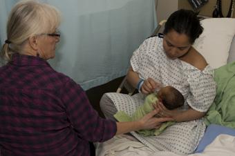 two women cup feeding newborn baby