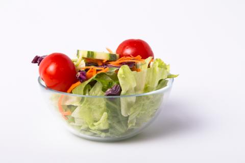 a salad with lettuce, cabbage, carrots, cucumbers and tomatoes