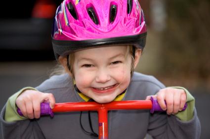 toddler on tricycle wearing her helmet