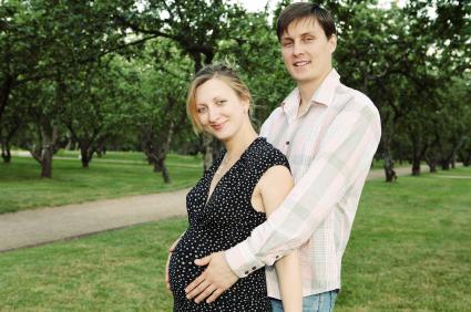 couple in field, man holding pregnant woman's belly