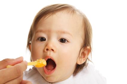 baby with mouth open being fed with a spoon