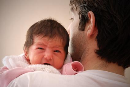 man holding crying baby on his chest