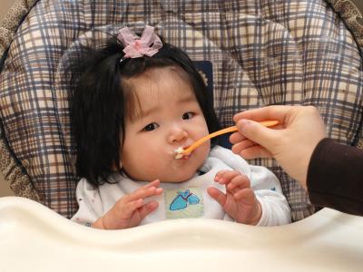 baby in high chair being fed with spoon