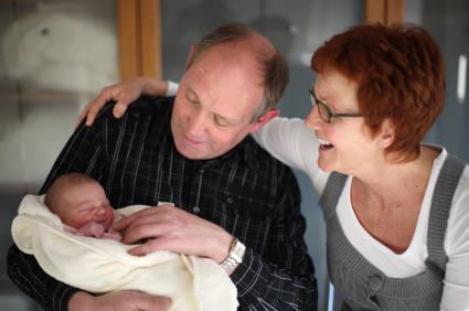 grandparents holding newborn baby wrapped in blanket
