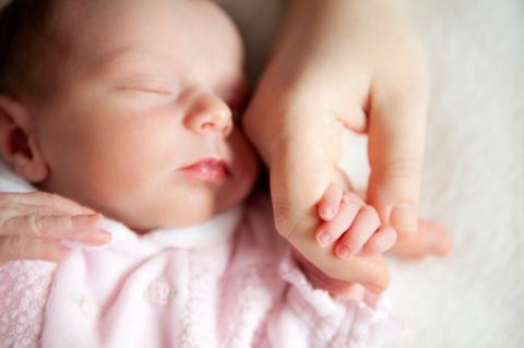sleeping newborn baby holding mothers hand