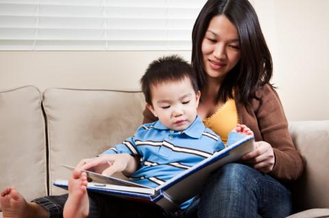 mom reading book to toddler on her lap