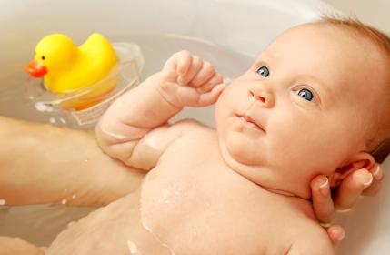 newborn baby getting a bath with rubber ducky