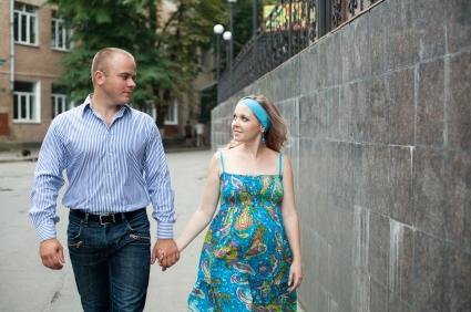 man and pregnant woman holding hands and walking