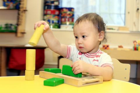 toddler sitting at table playing with blocks