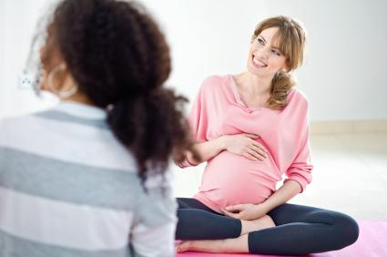 pregnant woman sitting on yoga mat holding belly