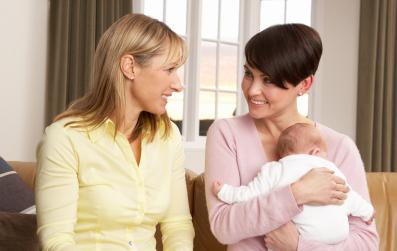 two women talking while one holds a newborn baby