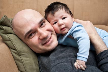 father laying on couch holding baby on his chest