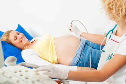 pregnant woman lying on back as nurse performs ultrasound exam
