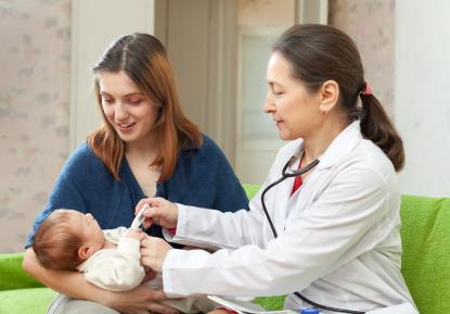 woman holding newborn baby while doctor examines