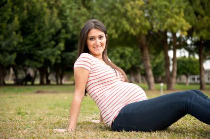 pregnant woman sitting down and leaning back in a field