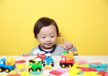 toddler playing with toy trucks and blocks