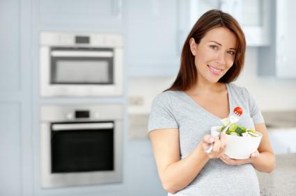pregnant woman eating a bowl of salad