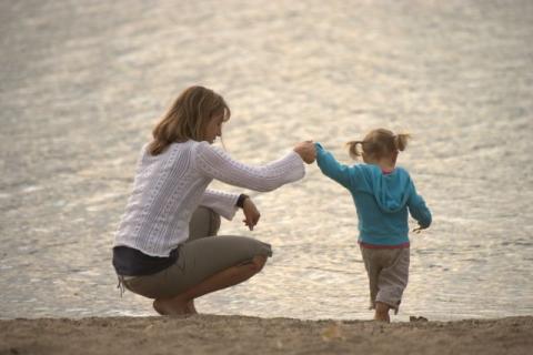 toddler walking on beach, mom holding her hand