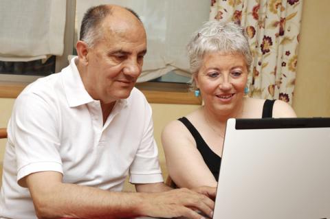two older adults looking at information on laptop
