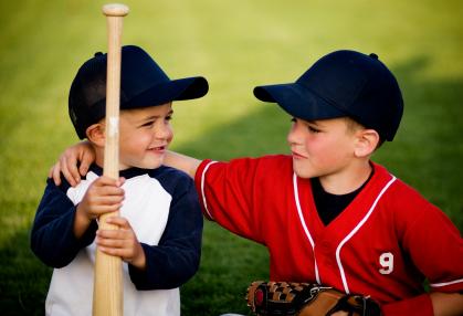 two boys with baseball uniforms and equipment