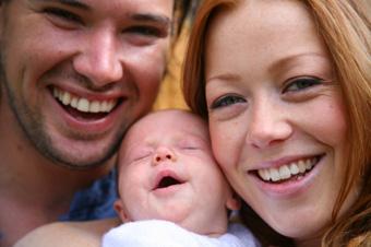 smiling man and woman with newborn baby
