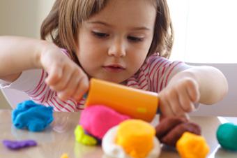 toddler playing with playdough and a rolling pin