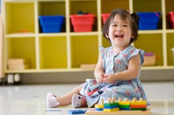 toddler smiling playing with blocks on floor