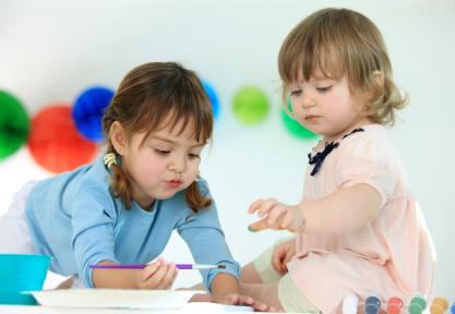 two toddlers playing with a paint set