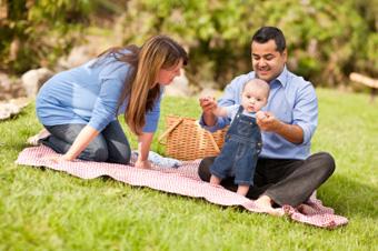 mom and dad playing with baby on blanket outdoors