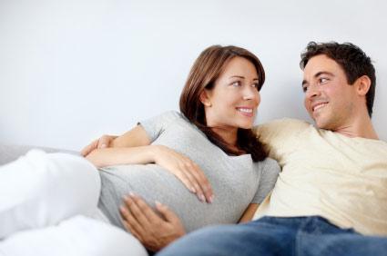 couple lounging, pregnant woman holding her belly