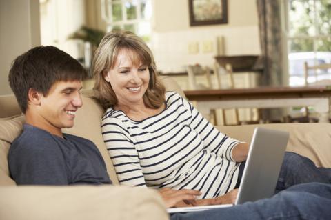 Mom and teen son on couch with laptop computer